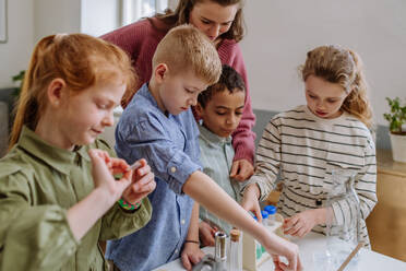 Junge Lehrerin bei einem Chemieexperiment mit ihren Schülern im naturwissenschaftlichen Unterricht. - HPIF31551