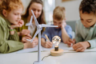 Junge Lehrerin mit einem Modell einer Windkraftanlage, die ihren Schülern etwas über Windenergie beibringt. - HPIF31582