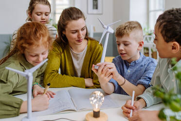 Junge Lehrerin mit einem Modell einer Windkraftanlage, die ihren Schülern etwas über Windenergie beibringt. - HPIF31583