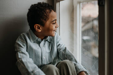 Little multiracial boy looking out of the window. - HPIF31587