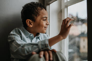 Little multiracial boy looking out of the window. - HPIF31588