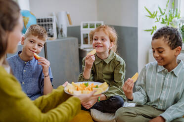 Teacher giving healthy fruit snack for pupils in school. - HPIF31604