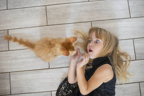 Nettes Mädchen liegt auf dem Boden und spielt mit Kätzchen zu Hause - ASHF00023
