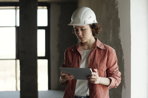 Ingenieur mit Schutzhelm und Tablet-PC auf einer Baustelle - DSHF01337