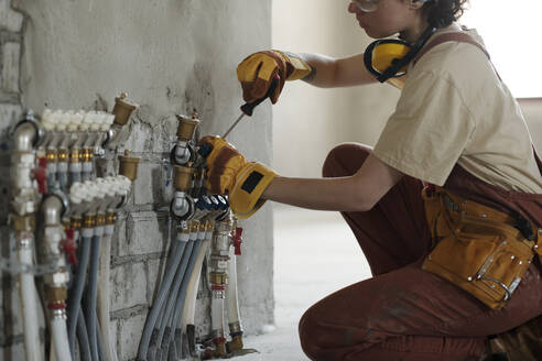 Elektriker bei der Arbeit mit Schraubenzieher auf der Baustelle - DSHF01352