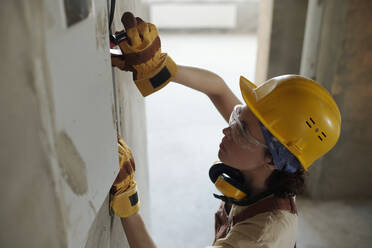 Elektriker mit Handschuh bei der Arbeit auf der Baustelle - DSHF01354