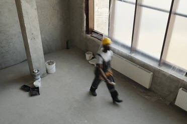 Bauarbeiter, der in der Nähe eines Fensters auf der Baustelle spazieren geht - DSHF01357