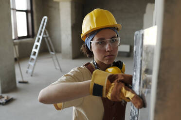 Bauarbeiter mit Schutzhelm bei der Arbeit auf der Baustelle - DSHF01358