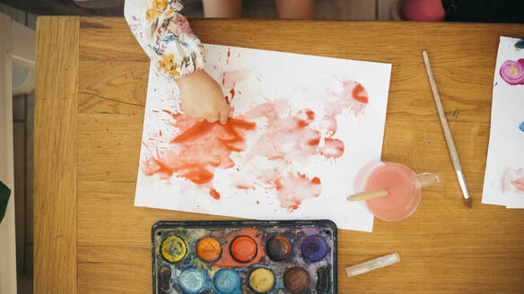 Hand eines Mädchens, das zu Hause mit Aquarellfarben auf Papier malt - ASHF00024