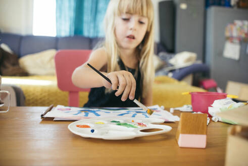 Mädchen mit Pinsel malt auf Papier zu Hause - ASHF00027