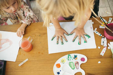 Mädchen macht Handabdruck mit Aquarellfarben auf Papier zu Hause - ASHF00032