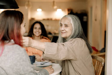 Smiling senior woman with daughter and granddaughter at home - MASF40585