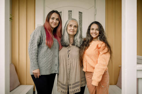 Porträt einer glücklichen älteren Frau mit Tochter und Enkelin auf einer Veranda - MASF40613