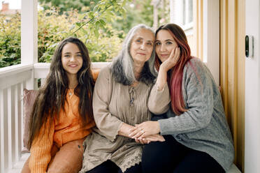 Portrait of multi-generation family sitting together at porch - MASF40615