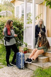 Multi-generation family with luggage outside house - MASF40646