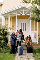 Happy multi-generation family waiting with luggage outside house - MASF40648