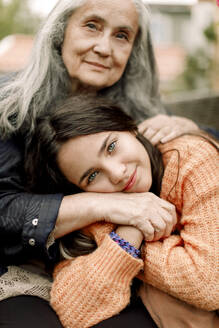 Porträt eines lächelnden Mädchens, das die Hand hält und seine Großmutter umarmt - MASF40650