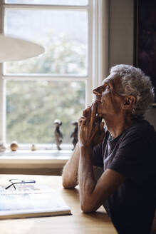 Senior man with eyes closed day dreaming on table at home - MASF40686