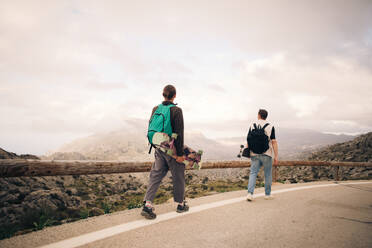 Freunde genießen die atemberaubende Berglandschaft beim Skateboardfahren in ihrem abenteuerlichen Urlaub - MASF40753