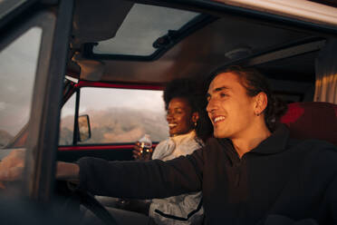 Ein glückliches Paar, das Abenteuer und Freiheit genießt, während es mit einem strahlenden Lächeln die offene Straße in seinem Van erkundet - MASF40778