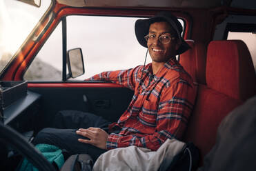 Ein zufriedener Mann im karierten Hemd, der seinen Urlaub genießt und sich in einem Van entspannt - MASF40820