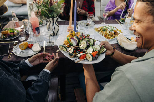 Zwei Freunde genießen eine gemeinsame Mahlzeit auf einer Dinnerparty, aufgenommen aus einer reizvollen Vogelperspektive - MASF40871