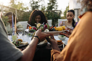 Freunde treffen sich bei leckeren Snacks zu einer lustigen Dinnerparty im Garten - MASF40872