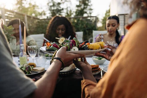 Friends bonding over delicious snacks at a fun-filled backyard dinner party - MASF40872