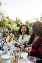 Eine fröhliche Frau genießt das Essen und die gute Gesellschaft mit Freunden bei einer Gartenparty - MASF40877