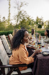 Eine Gruppe von Freunden versammelt sich im Garten zu einer köstlichen Mahlzeit mit viel Lachen und guter Gesellschaft - MASF40884