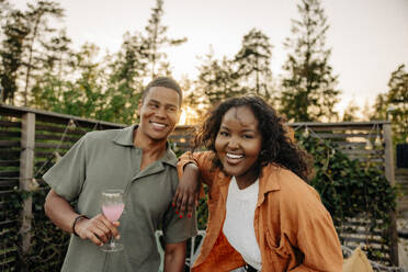 Portrait of happy woman with hand on shoulder of male friend holding drink glass at dinner party - MASF40891