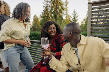 Friends raise their glasses in a joyful backyard gathering, celebrating good company and laughter - MASF40900