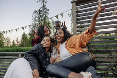 Portrait of male and female friends gesturing while celebrating during party in back yard - MASF40913