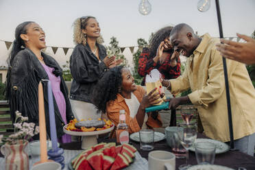 A young man surprises his female friend with birthday gifts at a backyard party - MASF40925