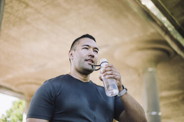 Man replenishes his energy with water during a strenuous workout, captured from a dynamic low-angle perspective - MASF40961