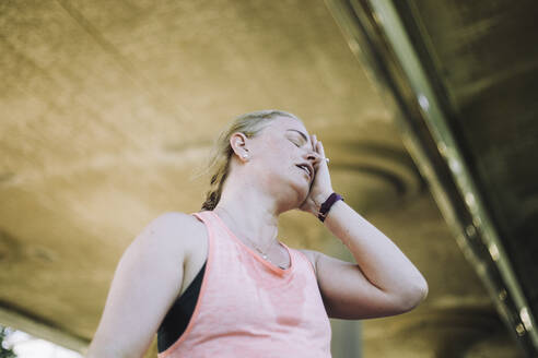 Eine müde Frau mittleren Alters ruht sich nach einem anstrengenden Workout aus, fotografiert aus einem niedrigen Blickwinkel. - MASF40965