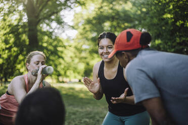Eine Trainerin motiviert ihr Team mit einem fröhlichen Lächeln während einer Trainingseinheit im Freien im Park - MASF40986