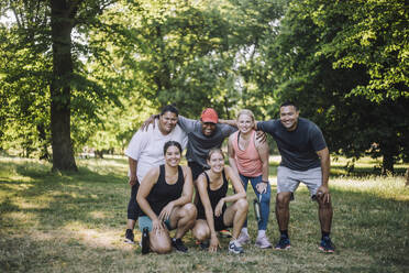 Eine bunt gemischte Gruppe von Freunden posiert glücklich für ein Foto nach einem erfolgreichen Workout im Park. - MASF40993