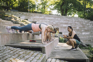 During a workout session on the steps, a female coach motivates her team to exceed their limits - MASF41006