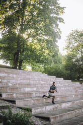 Ein Fitness-Enthusiast macht Ausfallschritte auf Parkstufen, um die Beinmuskeln zu stärken und die allgemeine Gesundheit zu verbessern. - MASF41025