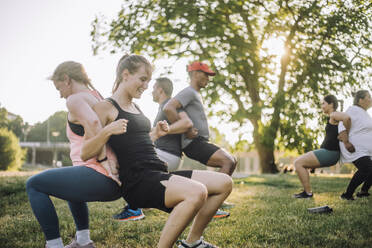 Eine fröhliche Gruppe unterschiedlicher Freunde, die sich beim Dehnen im Freien und bei einem Buddy-Stretch im Park zusammenfinden - MASF41034