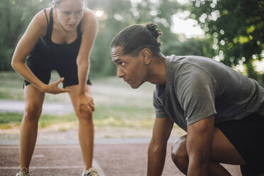 A determined man receives encouragement from his female coach before sprinting on the track - MASF41044