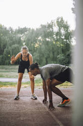 A female coach assists a male athlete in sprint training on the track - MASF41046
