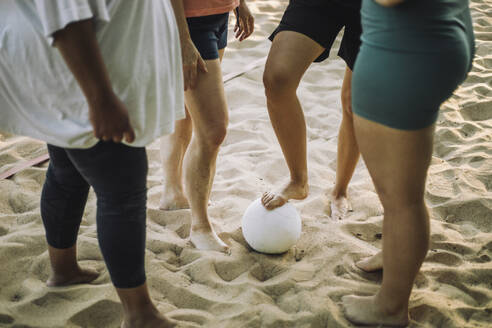 Eine fröhliche Gruppe von Frauen spielt Volleyball am sonnenverwöhnten Strand und genießt den warmen Sand und die Meeresbrise - MASF41059
