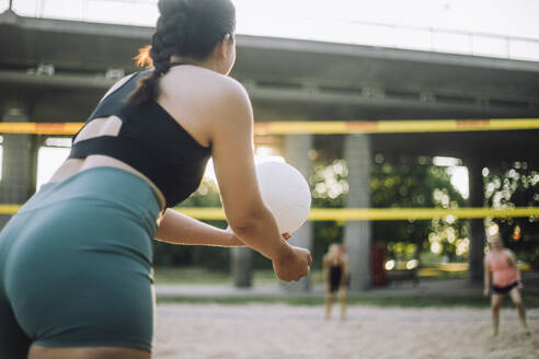Woman serving volleyball while playing with friend - MASF41061