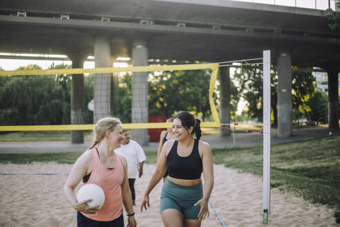 Strahlende Frauen, die mit Freude Volleyball spielen, während sie mit einem strahlenden Lächeln gehen - MASF41063
