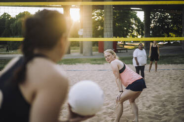 Eine Frau sieht ihre Freundin an, die einen Volleyball in der Hand hält, vielleicht in Erwartung eines Spiels oder in Erinnerung an alte Zeiten - MASF41066