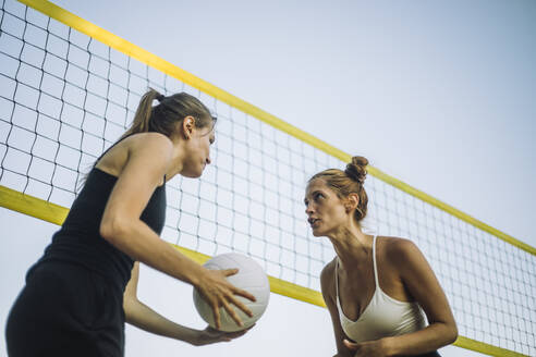 Eine Gruppe von Frauen genießt eine Partie Beachvolleyball unter blauem Himmel, was eine lustige und lebhafte Atmosphäre schafft - MASF41075