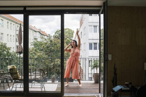 Eine unbekümmerte Frau tanzt auf ihrem Balkon, verloren im fröhlichen Rhythmus der Musik - MASF41079