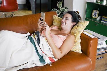 Eine Frau, die ihre Freizeit zu Hause genießt, vertieft in ihr Telefon - MASF41126